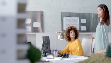 happy diverse female colleagues using computer and discussing work at desk, copy space, slow motion