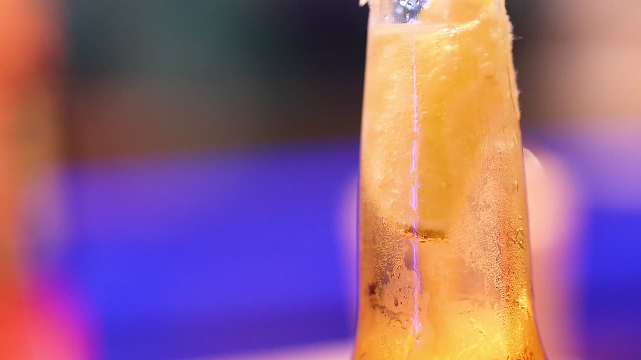 A detailed view of a beer bottle with lime, showcasing condensation and vibrant background colors.