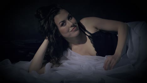 mujer sensual en la cama se sienta y sonríe expectante al espectador
