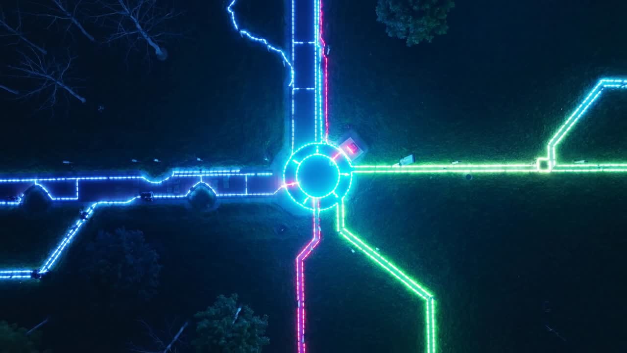 Pulsing neon roundabout and paths responding to slight pulse at night in park, red fixture, bench
