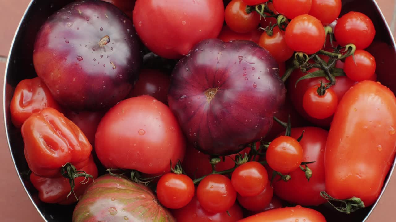 Colorful organic tomatoes. Mix tomatoes background, Several varieties of sliced tomatoes top view. Different assorted colorful tomatoes, heirloom, cherry, rose, beefsteak, cocktail, grape, purple.