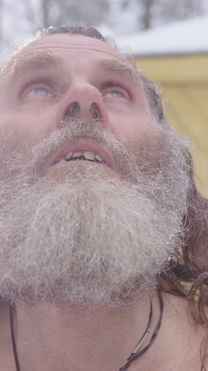 Spiritual hippy man look skyward in worship after sauna in snow flurry, vertical