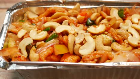 Cashew-nut-salad-in-a-takeaway-packet-on-table-,