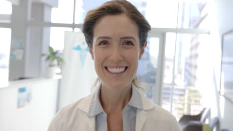portrait of happy caucasian female doctor smiling in hospital reception, slow motion