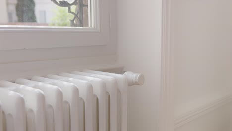 woman turning down heating adjusting radiator