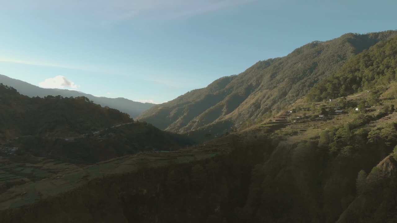 Ampia ripresa aerea che si allontana su una valle montuosa coperta di alberi, terreni agricoli a Kabayan, Benguet, Filippine.
