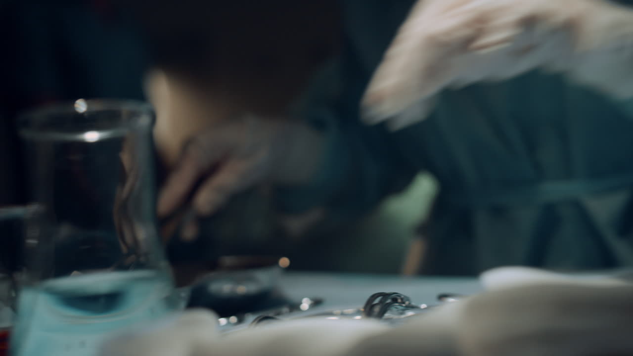 Nurse preparing sterile instruments on table in dark emergency room closeup.