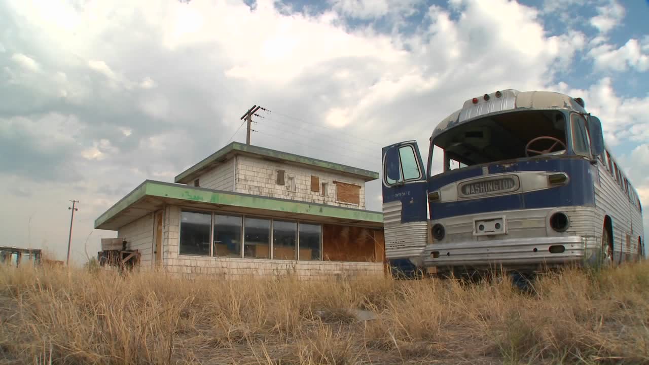 un tiro de lapso de tiempo en movimiento de un autobús galgo abandonado en un campo 1