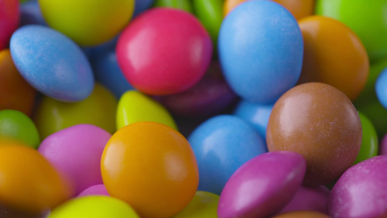 movimiento lento de primer plano de caramelos de chocolate redondos de colores, dragee. rotación y caída de caramellos de chocolate multicolores