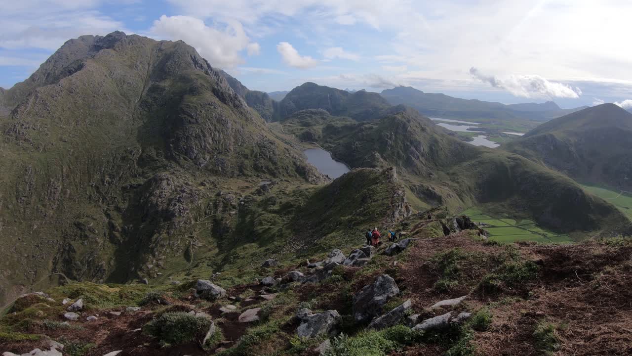 un grupo de excursionistas camina por el sendero desde la cima de la montaña mannen en la playa haukland en lofoten, noruega
