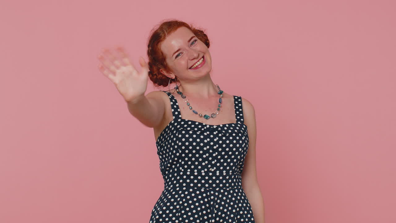 joven bonita sonriendo amistosamente a la cámara y agitando las manos gestando hola o adiós, bienvenida