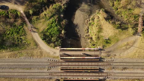 AERIAL---Bicycle-crossing-over-a-bridge-next-to-railway-in-Maschwitz,-Argentina