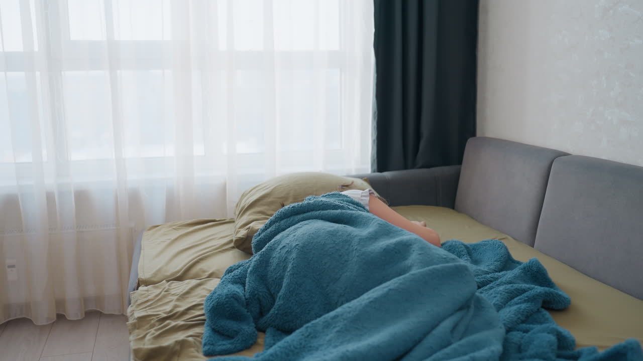 Caucasian Woman Office Worker Stretching And Sitting Up On Sofa Bed, Teal Blanket Tossed, Soft Daylight Through Curtains, Scene Of Groggy Wakefulness And Slow Start