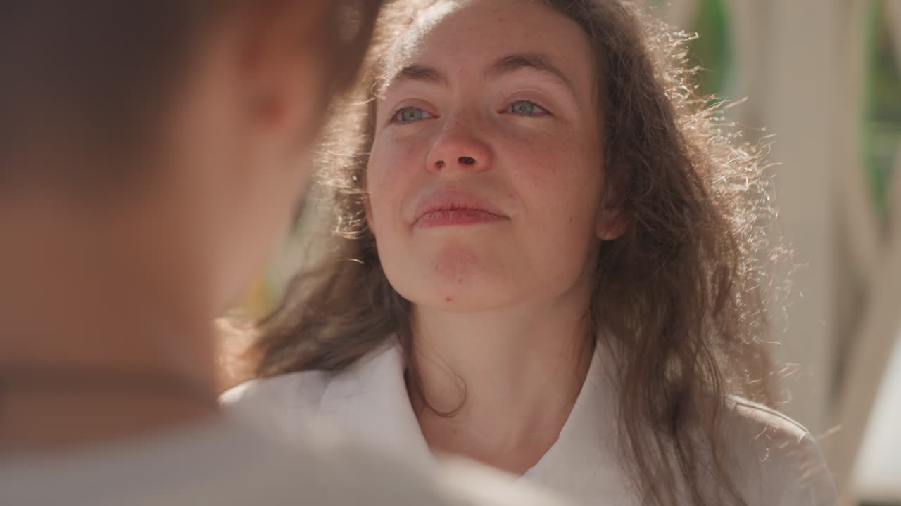 Closeup woman listening to partners words. Imagined teacher role absorbs a tearful, hopeful promise about family and future, soft backlight outlines hair, gentle smile and nod, intimate exchange