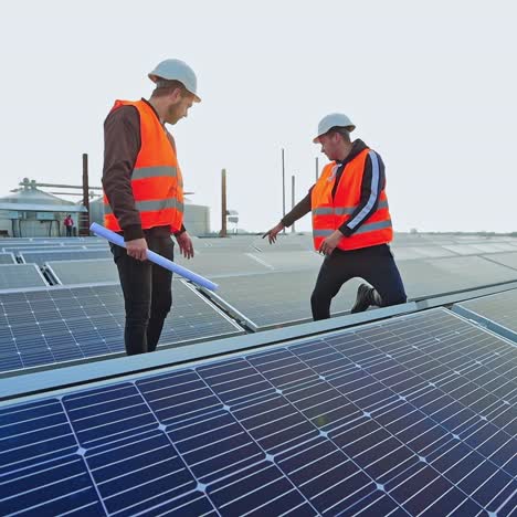 enginneers installing new sunny batteries. two workers in a uniform and hardhat installing photovoltaic panels on a solar farm.