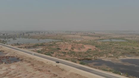 Drone-capture-the-aerial-view-of-the-car-driving-through-the-highway-with-trees-at-the-side-of-the-road-near-Khairpur,-Sindh,-Pakistan