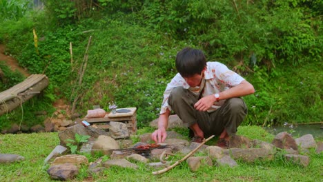 素朴なバーベキューを作る田舎の緑の地面で食べるアジアの若い男