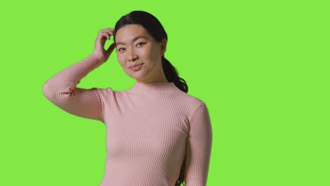 studio portrait of smiling confident independent woman standing against green screen