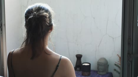 Free-woman-praying-at-improvised-place-of-worship-with-a-statue-of-Buddha-and-a-candle