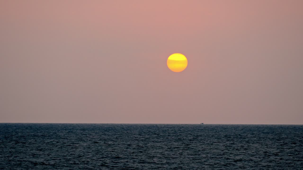 Golden hour over the ocean in Galle, Sri Lanka. The sun sets slowly on the horizon, casting warm hues across the calm sea.