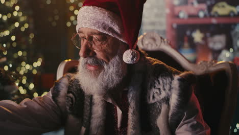 santa claus reading a letter by the christmas tree