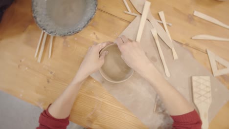 hands of female potter smoothing inner surface of earthenware vessel