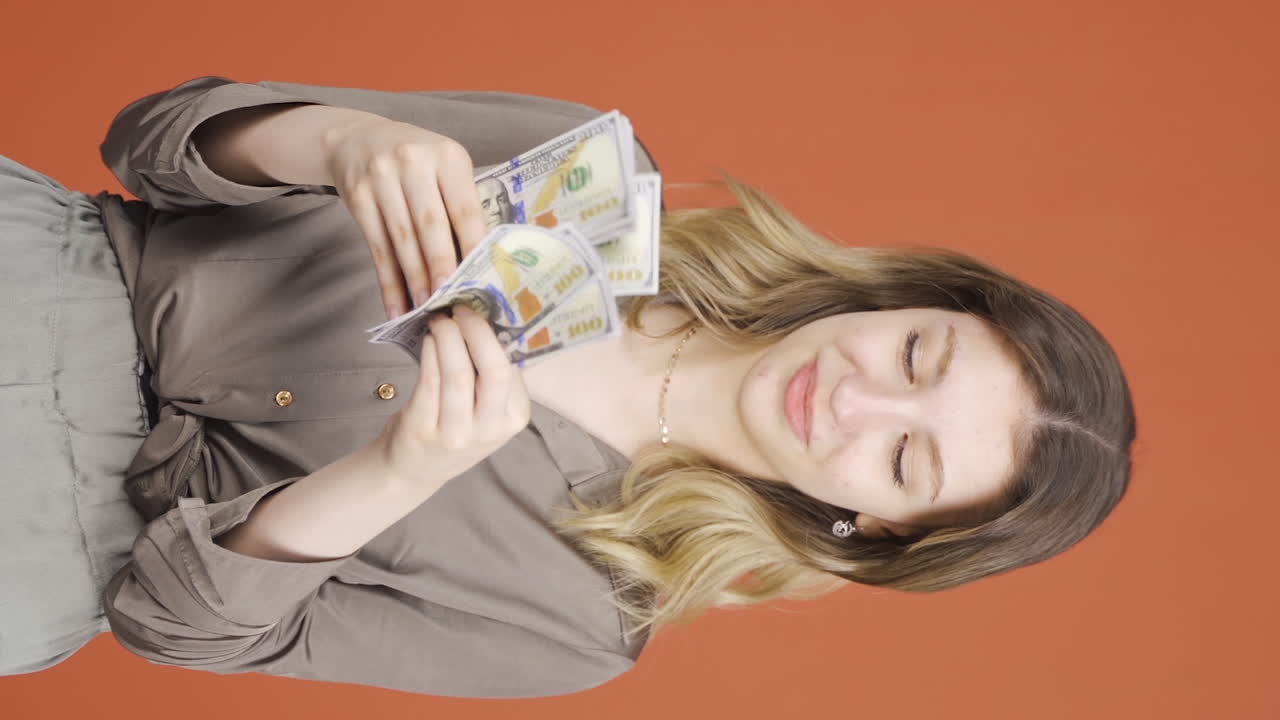 카메라를 바라보며 돈을 세는 젊은 여성의 수직 비디오.