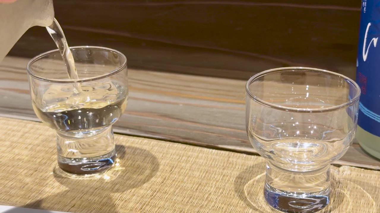 木製のテーブルに置かれたグラスに、陶器の器から透明な日本酒が注がれる。