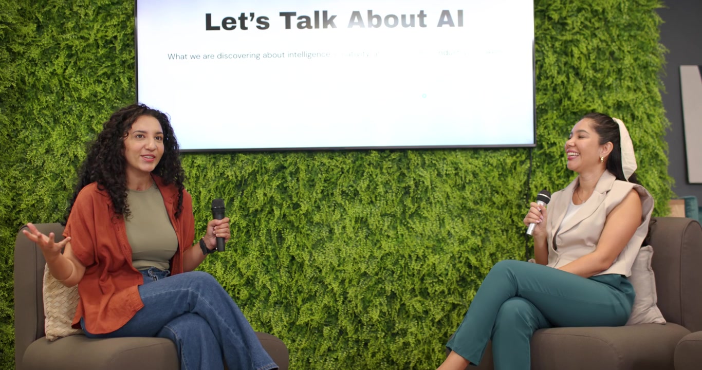Diverse women cohosts responding to AI title left speaking right nodding with mics in lounge