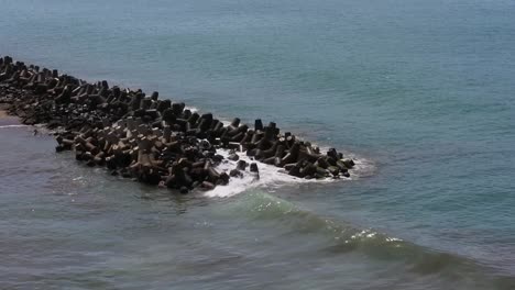 las olas del océano chocando contra el rompeolas en un día soleado