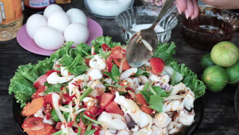 primer plano persona manos con cuchara sirviendo deliciosa ensalada de calamar picante fresco