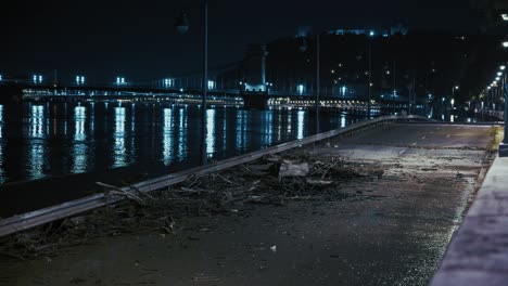 nighttime view of a flood damaged riverbank in budapest with debris scattered across the path