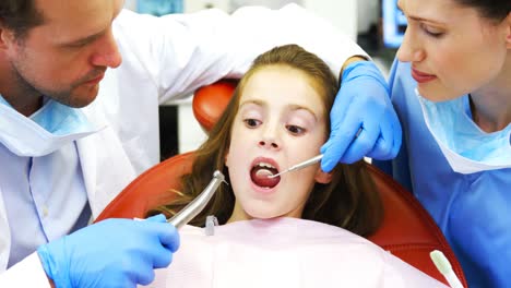 dentists examining a young patient with tools