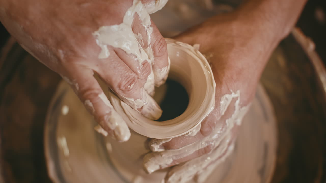 manos moldeando arcilla en una rueda de cerámica