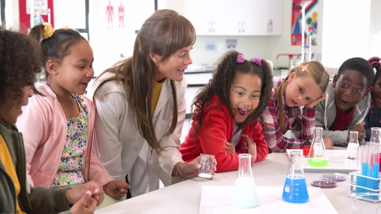 Teacher and diverse students amazed by colorful science experiment in classroom