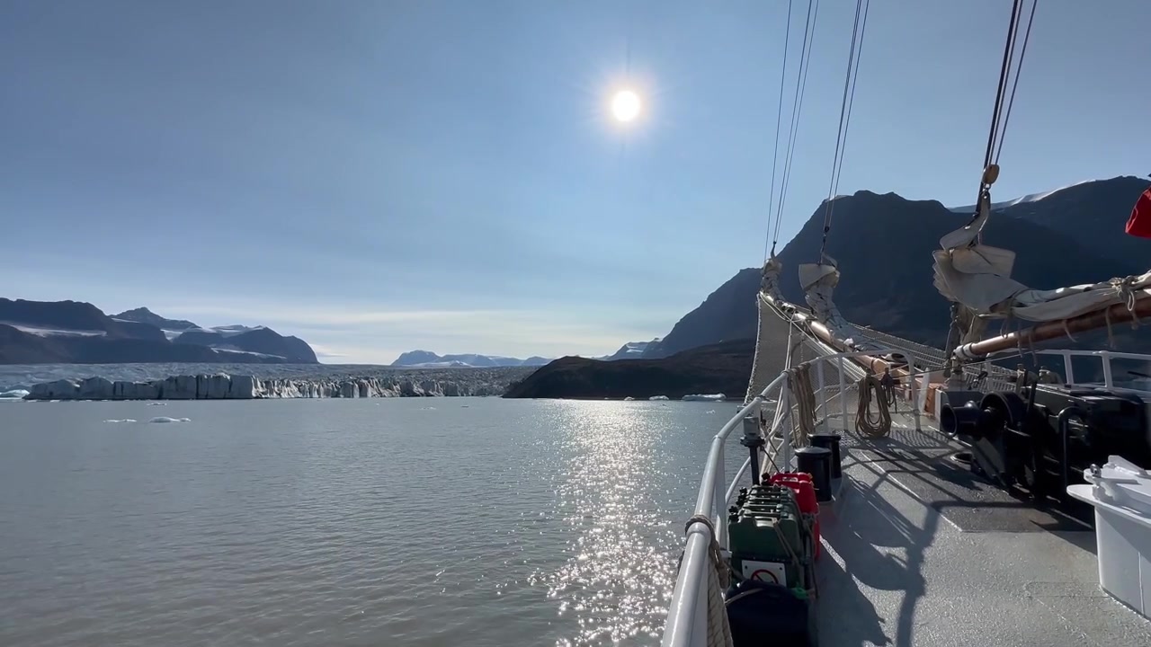Ein Reisender blickt mit einem Fernglas auf einen Gletscher in Vikingebugt, Scoresbysund, Grönland.