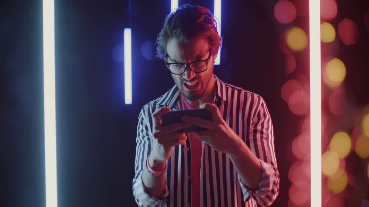 Man Playing a Game on Smartphone in Neon Lighting