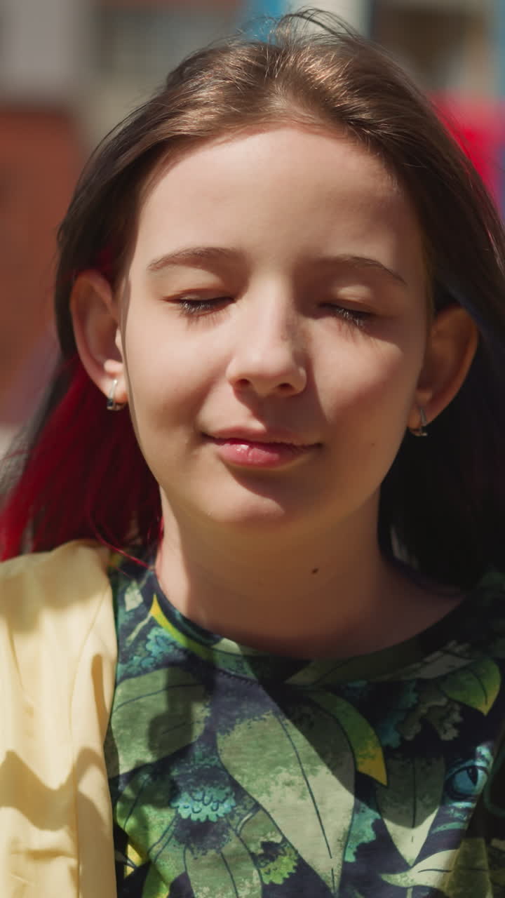 joven mujer cierra los ojos sonriendo soñador. chica se sienta en el columpio en la ciudad ruidosa e imagina aventuras interesantes de cerca en el fondo borroso