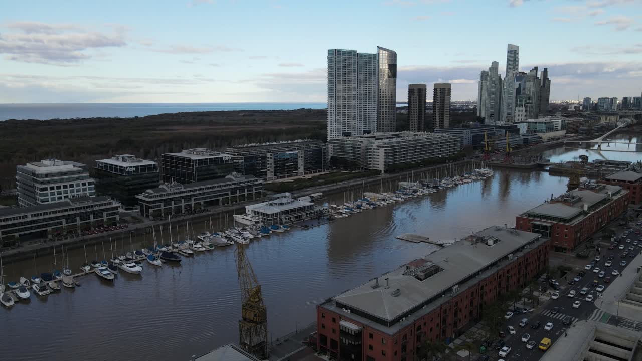 vuelo aéreo sobre el paseo marítimo de puerto madero con barcos de atraque en el distrito central de negocios de buenos aires