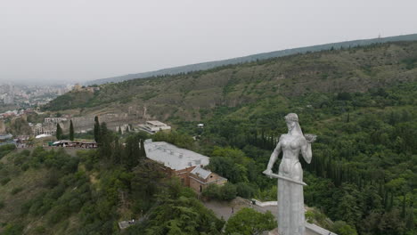 toma aérea de dolly out del monumento a la madre de georgia durante un día sombrío