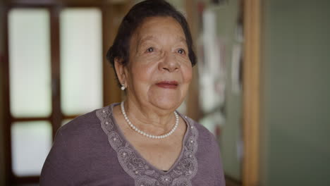 retrato de una mujer de raza mixta de edad avanzada elegante sonriendo feliz mirando por la ventana disfrutando de un estilo de vida de jubilación relajado