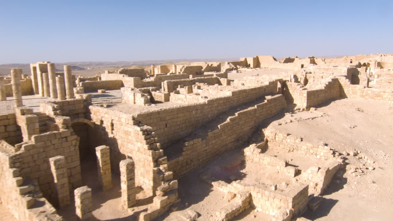 Aerial flyover of ancient stone Avdat ruins on mountain plateau in desert
