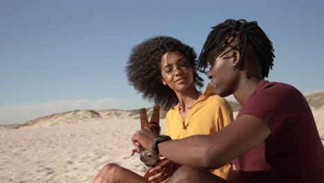 Couple-toasting-beer-bottles-on-the-beach-4k