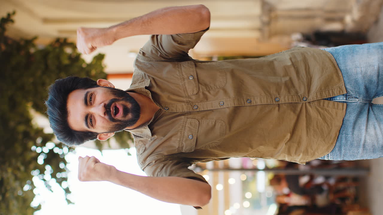 Young man shouting celebrating success winning goal achievement good victory news in city street