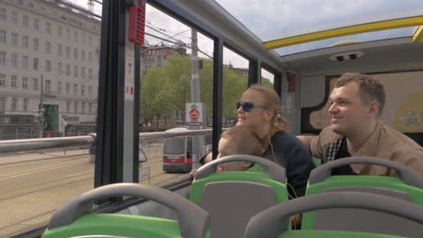 Family-of-three-traveling-in-city-by-double-decker-bus