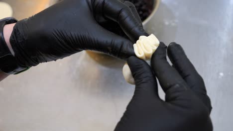 the chef wraps the dough with berries to form a pierogi