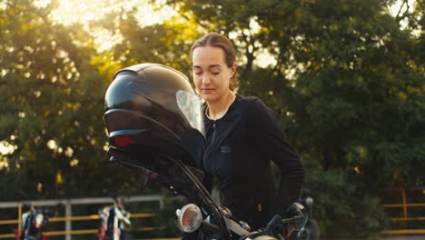 A-girl-gets-behind-the-wheel-of-a-motorcycle-and-puts-on-a-helmet-before-her-motorcycle-driving-training-in-a-motorcycle-school-in-sunny-weather