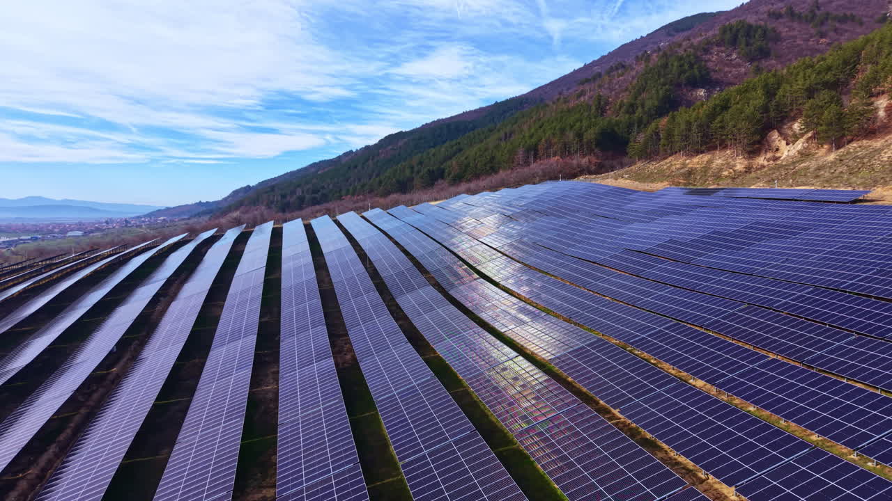 Solpaneler installeret på en bjergskråning fanger sollys på et energiproduktionsanlæg på en klar dag