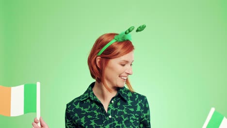 Portrait-of-playful-woman-waving-Irish-flags