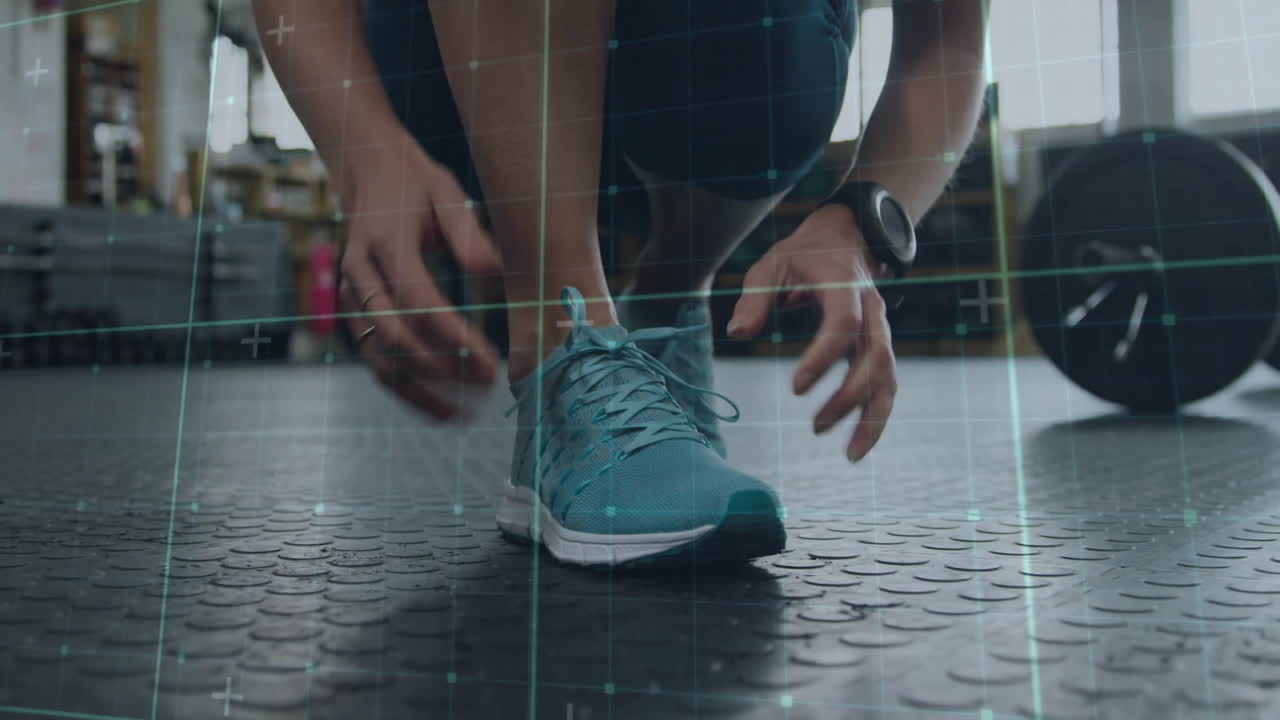 Person tying shoelaces in gym with digital grid overlay animation